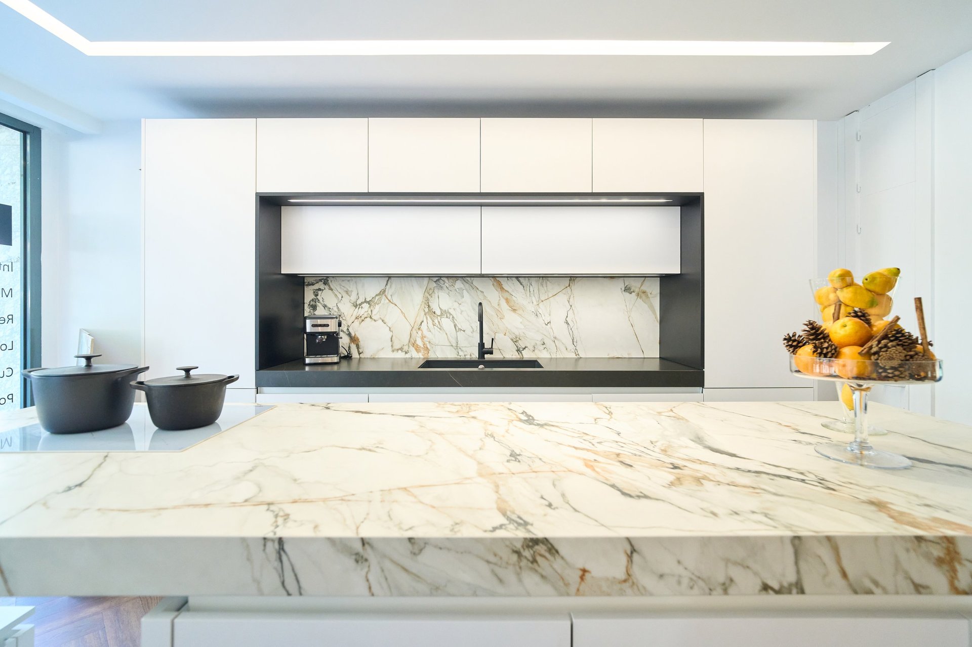 Luxurious kitchen showcasing a marble island, white cabinets, and modern appliances, creating a stylish and functional space